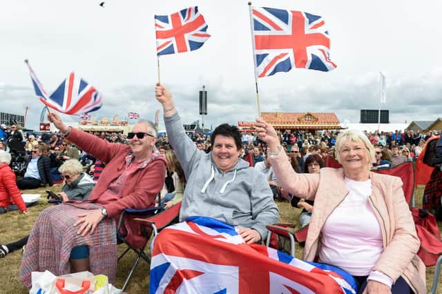Sarah Hobbs, Mary Tupper and Pear Newman wave Union Jack flags during the National Commemorative Event on Southsea Common during the D-Day events.