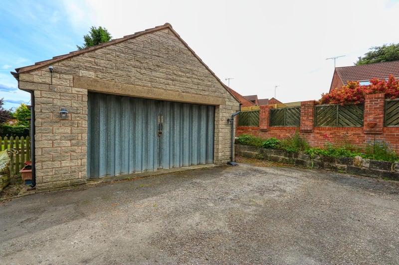 The detached double garage is approached by a drive which contains space for several parked cars.