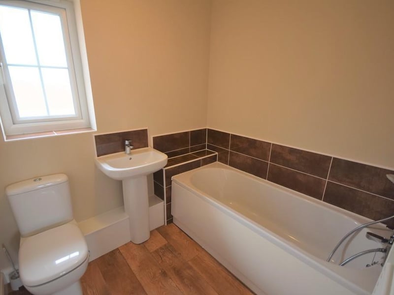 Bathroom - A contemporary three piece bathroom suite having a panelled bath with chrome shower hose, low flush wc, wash hand basin with chrome mixer tap and co-ordinating tiled splashback, wall mounted towel rail, extractor fan and double glazed obscure window.