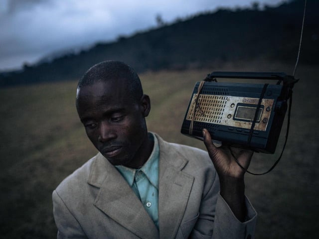A displaced man stands at the top of a hill to pick up the radio signal and listen to the news near the internally displaced persons camp of Bijombo.