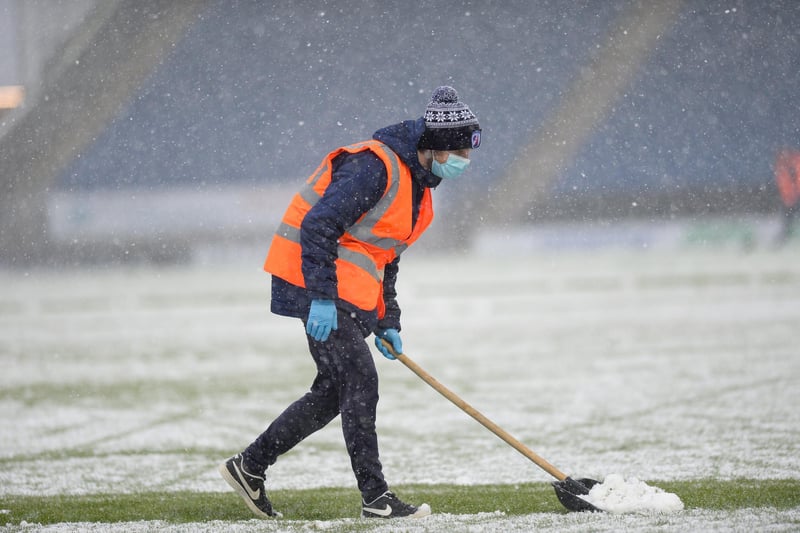 Volunteers clear snow from the Technique pitch ahead of the game.