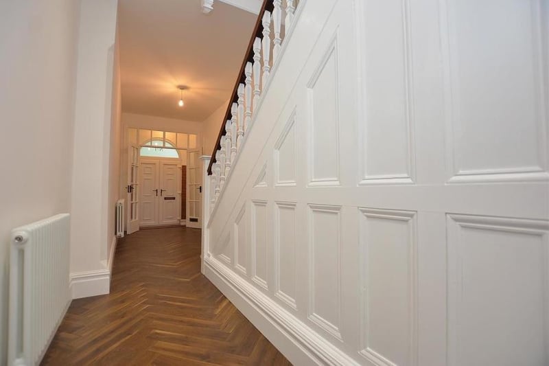 A welcoming hall features a high ceiling, new parquet flooring, LED spotlights, two feature column radiators and understairs storage cupboards. A wide, traditional staircase leads to the first-floor landing.