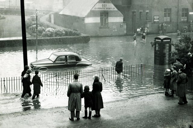 Passers-by pause to look at a car stranded in the flood water at Firth Park terminus... the car belonged to the Deputy Lord Mayor, Coun Oliver S Holmes, August 21, 1954
