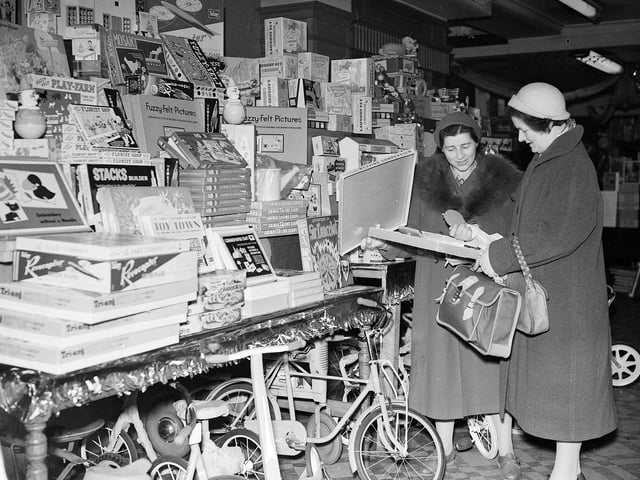 Two women inspect a weaving compendium while Christmas shopping at Thorntons on Princes Street in 1958.