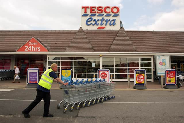 A Tesco employee pushes a stack of trolleys past the entrance to the Tesco Extra superstore  (Photo by Oli Scarff/Getty Images)