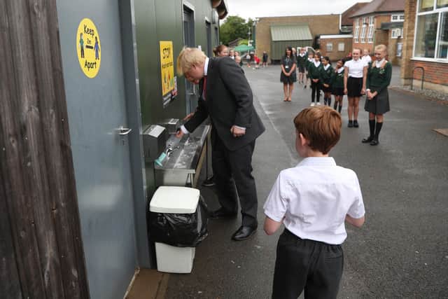 Britain's Prime Minister Boris Johnson washes his hands at a sink in the playground (Photo by STEVE PARSONS/POOL/AFP via Getty Images)