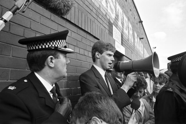 A policeman watches as Shareholders' Association chairman Ewan Stewart addresses the hundreds of angry Hibs fans who turned up at Easter Road football stadium after hearing Hearts chairman Wallace Mercer planned a takeover of their club in June 1990.