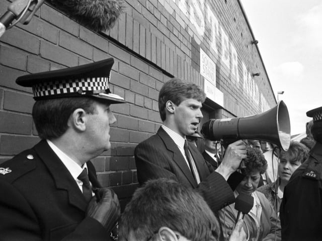 A policeman watches as Shareholders' Association chairman Ewan Stewart addresses the hundreds of angry Hibs fans who turned up at Easter Road football stadium after hearing Hearts chairman Wallace Mercer planned a takeover of their club in June 1990.