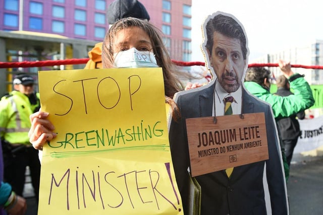 A climate activist stands with a cut-out of Brazil's Environment Minister Joaquim Leite