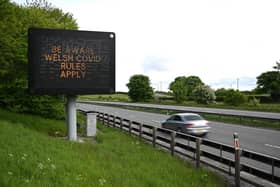 A sign notifying travellers to observe Wales' Covid-19 rules is displayed alongside the A55 motorway near Flint, north Wales  (Photo by OLI SCARFF/AFP via Getty Images)