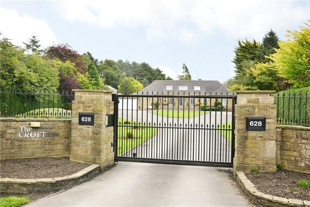 The property is accessed via electric gates and boasts a large driveway with a central turning circle, and well manicured lawns on either side.