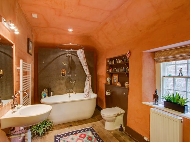 The bathroom is certainly not small, boasting a stylish free-standing bath with a shower over