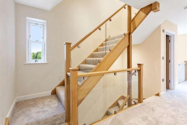 The hall gives access to the lounge or sitting room, and also a utility room, which has a wall-mounted boiler, sink and drainer unit, and fitted units and worktops, plus space for a washing machine and tumble dryer. The hall's oak staircase leads us up to the first floor.