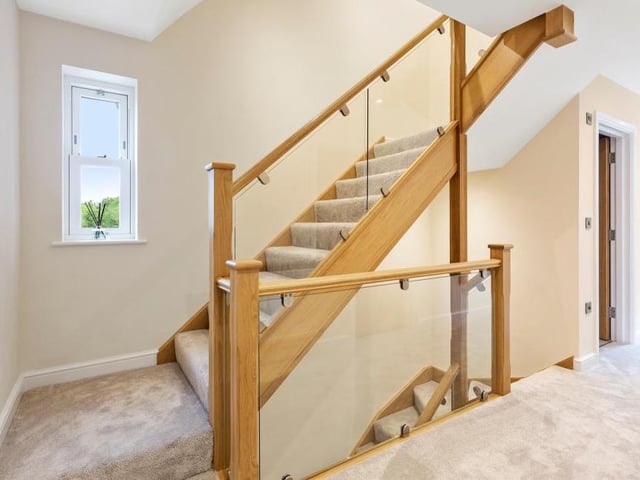 The hall gives access to the lounge or sitting room, and also a utility room, which has a wall-mounted boiler, sink and drainer unit, and fitted units and worktops, plus space for a washing machine and tumble dryer. The hall's oak staircase leads us up to the first floor.