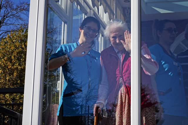 Staff members pictured with residents waving through the Conservatory Windows. Picture: NSST-26-03-20 Bridgedale 4-NMSY