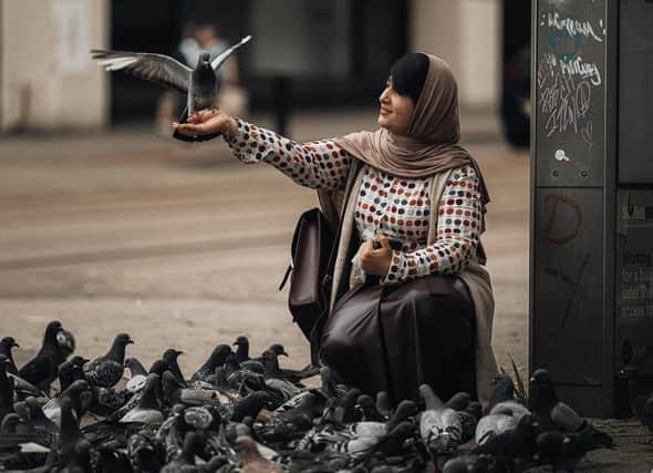 A pigeon sits on a woman's hand near the Castle Square tram stop in Sheffield city centre in this photo by Josh Anelli