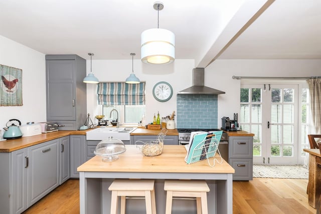 The kitchen features an island, a double Belfast sink inset into the wooden work surface, and engineered oak flooring. There is a five-ring Belling gas range, an integrated dishwasher and space for a fridge freezer. A stable door leads outside.