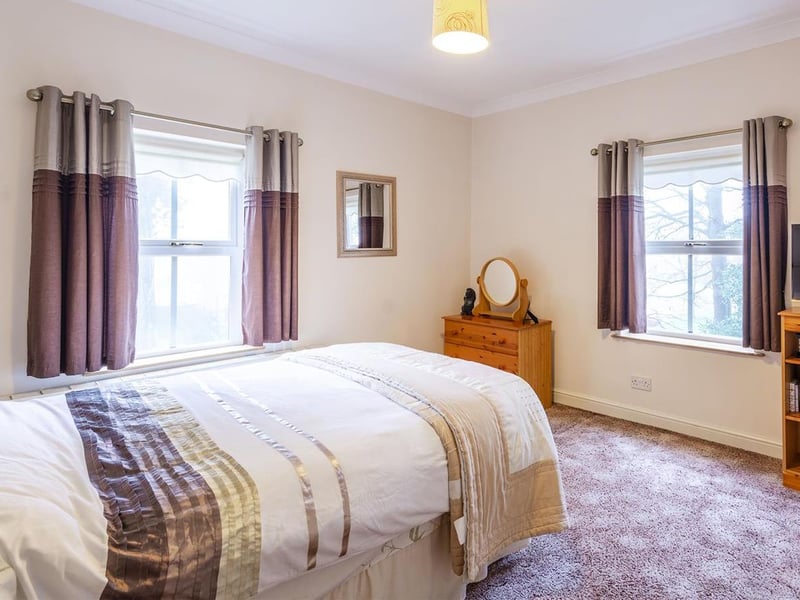 With carpet to flooring, central heating radiator, cupboard for additional storage and dual-aspect windows to the side and the rear elevations.