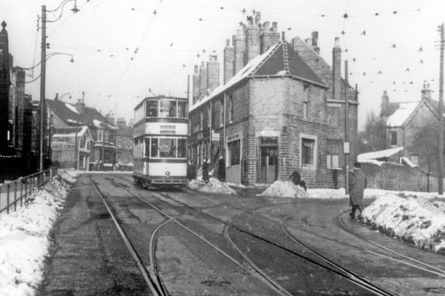 A tram travelling along Crookes, with Crookes Post Office, Crookes Endowed Schools and the tram tracks to Pickmere Road Tram Depot visible, in 1955