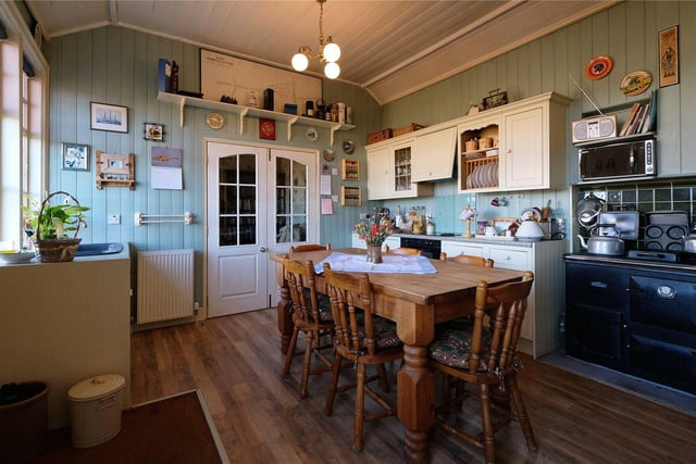 The dining kitchen with timber panelled walls, wall and floor units and an oil fired Rayburn.
