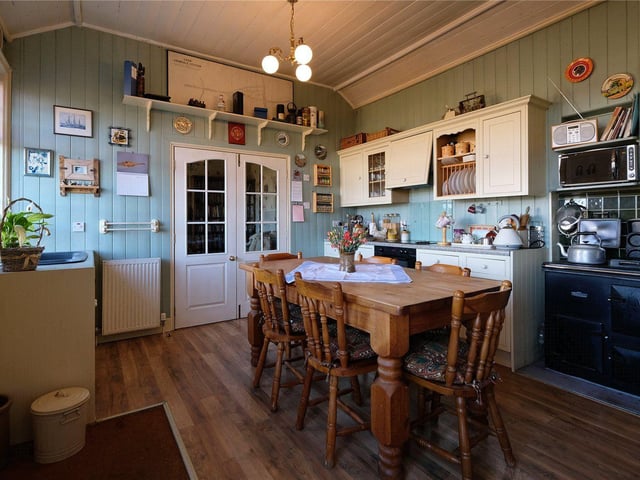 The dining kitchen with timber panelled walls, wall and floor units and an oil fired Rayburn.