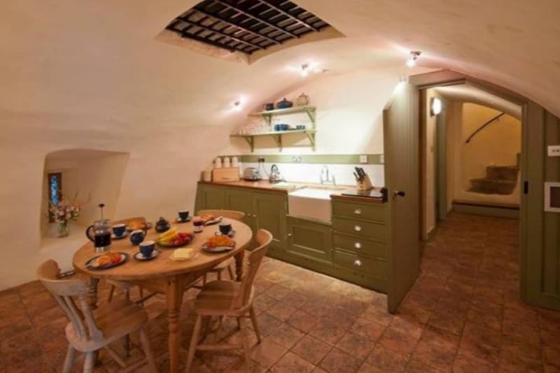 The kitchen features a vaulted ceiling and an original iron grill.