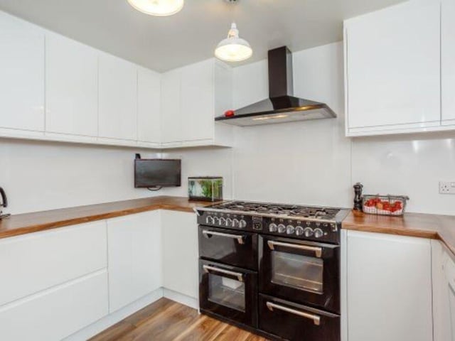 The modern kitchen has white gloss unites and a range style cooker.