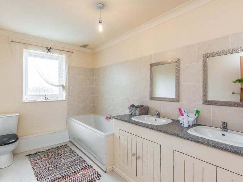 The main bathroom is attractive, fitted with a suite that comprises a panelled bath, low-level WC and double-sink unit. The walls are part-tiled, while there is an obscured window to the back.