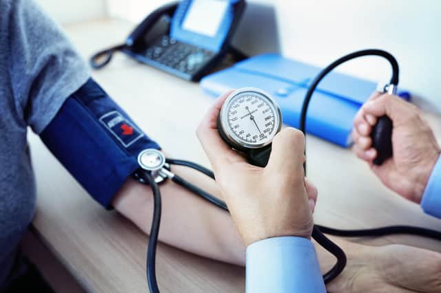 A doctor checking the blood pressure of a patient (photo: Adobe).