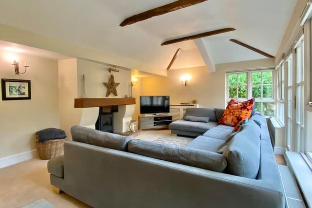 This is the family room or garden room, complete with a gas coal-effect burner and flagstone hearth. It boasts a vaulted beam ceiling, while double-glazed doors lead to the main garden.