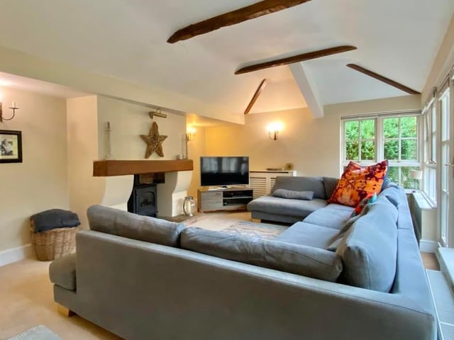 This is the family room or garden room, complete with a gas coal-effect burner and flagstone hearth. It boasts a vaulted beam ceiling, while double-glazed doors lead to the main garden.