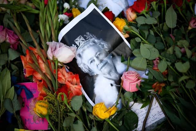 A photograph of Queen Elizabeth II lies among the flowers at a memorial site in Green Park near Buckingham Palace following the death of the queen on September 8.  (Photo by Chip Somodevilla/Getty Images)