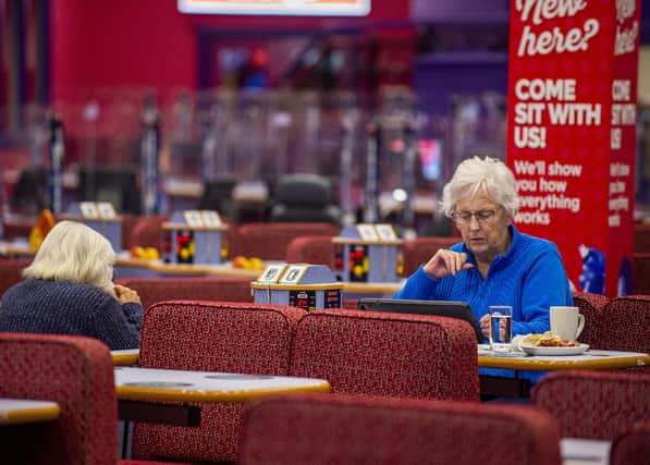 A customer at Buzz Bingo is enjoying a cup of tea and  snack as she plays the game.