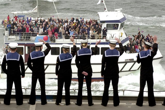 Sailors aboard HMS Ark Royal wave to a civilian vessel full of well wishers welcoming the aircraft carrier home 15th May 2003. Picture: Jonathan Brady 032429-17