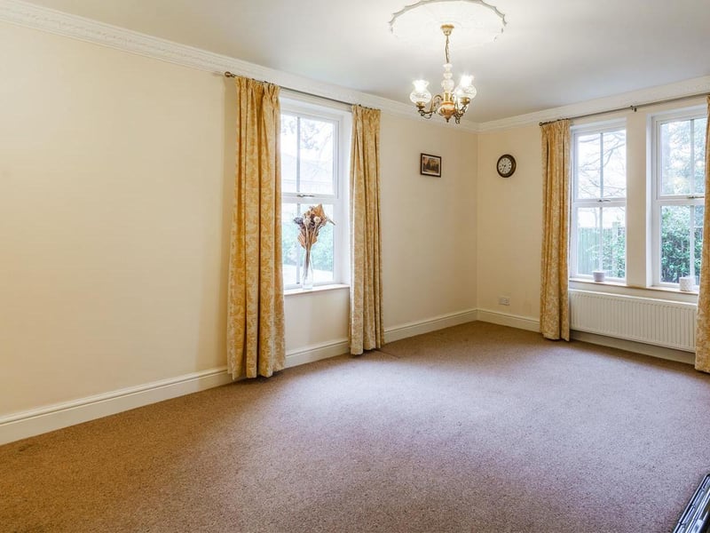 With carpet to flooring, feature fireplace with surround and dual-aspect windows to the side and rear elevations.