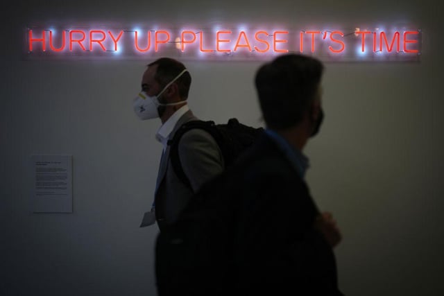 Delegates walk past a neon light art installation by artist Cornelia Parker during COP26 at the SEC