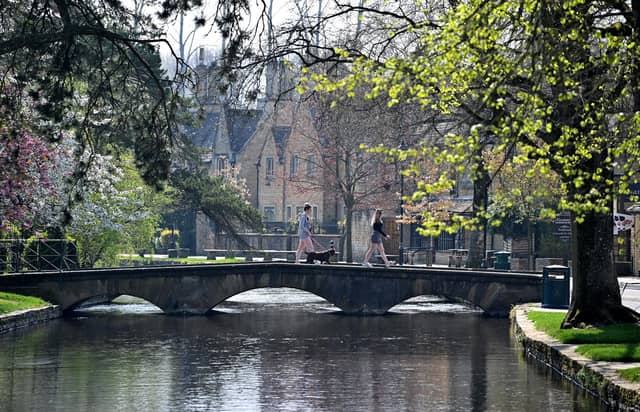 A woman walks with a dog across a bridge in the Cotswolds. (Photo by JUSTIN TALLIS/AFP via Getty Images)