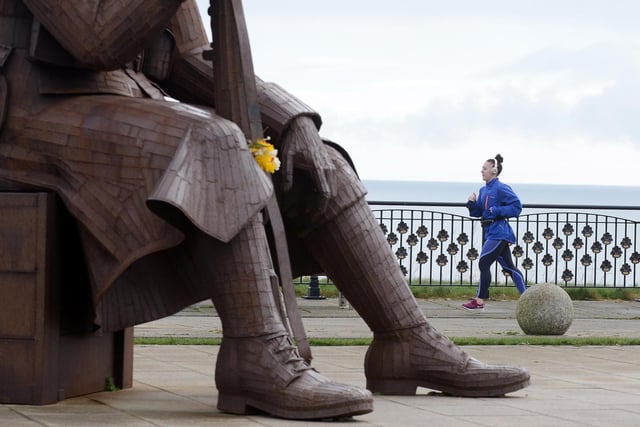 A jogger takes in the seafront on Terrace Green under the eye of Tommy.