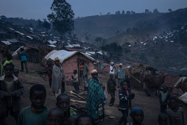 Displaced girls and boys from the Bafuliru community stand amidst the makeshift shelters of the internally displaced persons camp of Bijombo.
