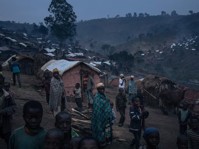 Displaced girls and boys from the Bafuliru community stand amidst the makeshift shelters of the internally displaced persons camp of Bijombo.