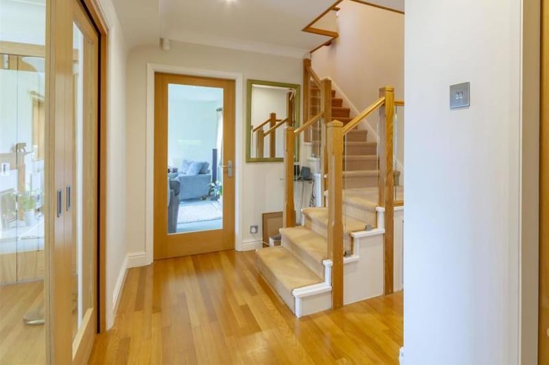 A welcoming hallway with a carpeted staircase and a glass balustrade leading to the first floor. There are two central-heating radiators.