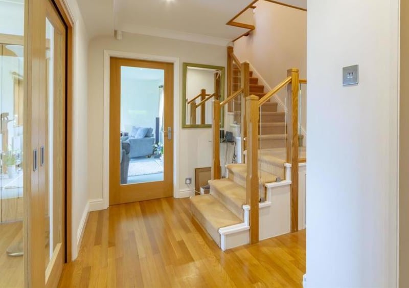 A welcoming hallway with a carpeted staircase and a glass balustrade leading to the first floor. There are two central-heating radiators.