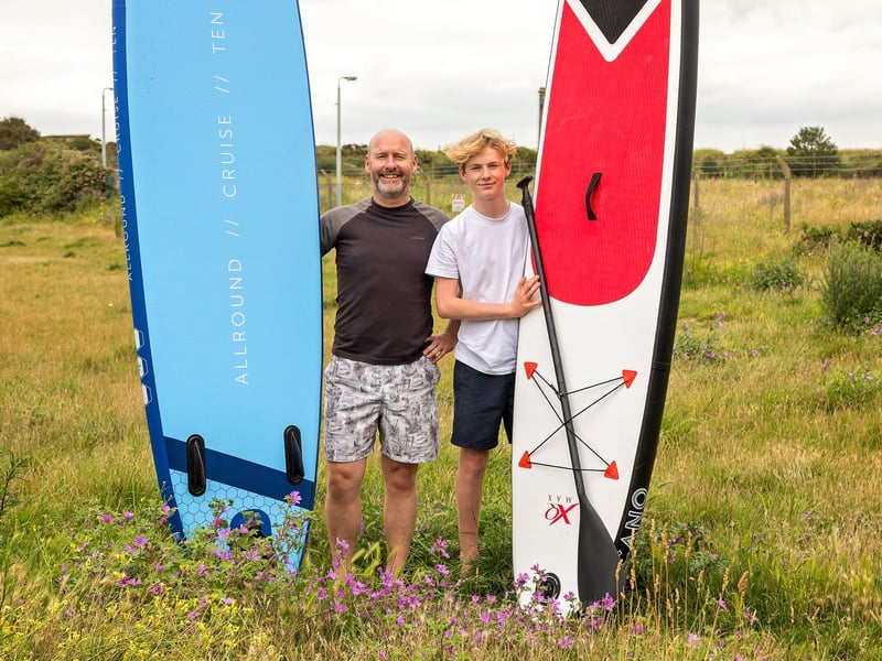 Graham O'Neil (49) and son Owen O'Neil (15) trek across the moorland by Fort Cumberland to enjoy an afternoon at the beach with their Stand Up Paddle Boards. Picture: Mike Cooter (150721)