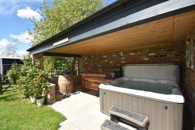 An outdoor hot tub sits nestled in the courtyard, with a wooden bar area located alongside.
