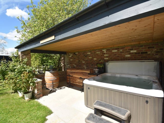 An outdoor hot tub sits nestled in the courtyard, with a wooden bar area located alongside.