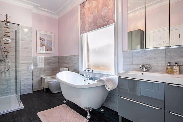 The en-suite has a white suite with a roll-top freestanding bath, twin wash hand basin and a large shower enclosure.