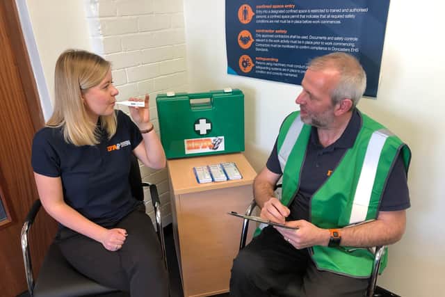 Gemma Shaw, credit controller, takes her temperature and Marius van der Colff, health, safety and environment manager.