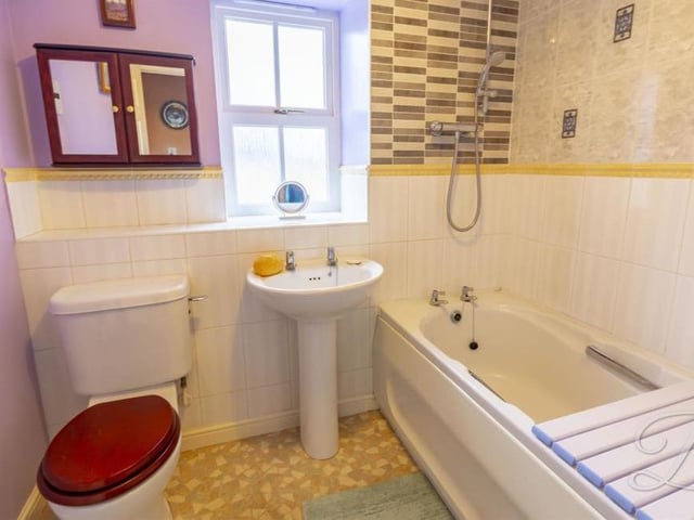In between the third and fourth bedrooms is this family bathroom. The bath has an overhead shower, while there is also a low-flush WC and pedestal wash basin.