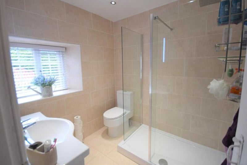 A very modern and contemporary ensuite with a walk-in Mira electric shower, w.c., wash basin, tiled floor, down lights, chrome towel rail,