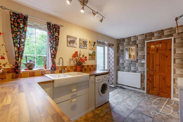This spacious room contains traditional cabinets and units, a Belfast sink and plumbing for a washing machine.